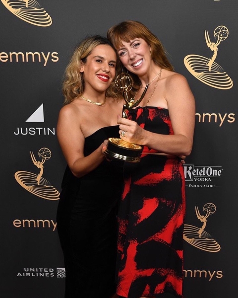 Two women pose with an Emmy award.