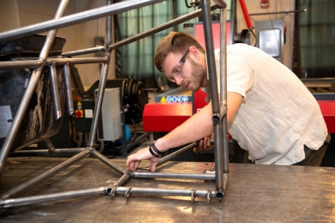 Elliot Thorp works on the steel frame of a go-kart