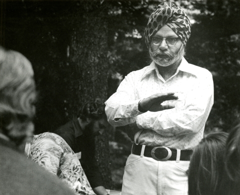 Professor Balwant Singh wears a white shirt, glasses and a turban. He is speaking to students. The image is black and white.