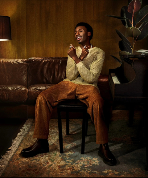 Stephen Leslie sits in a chair with his head back, eyes closed, and arms crossed in front of him as he smiles.