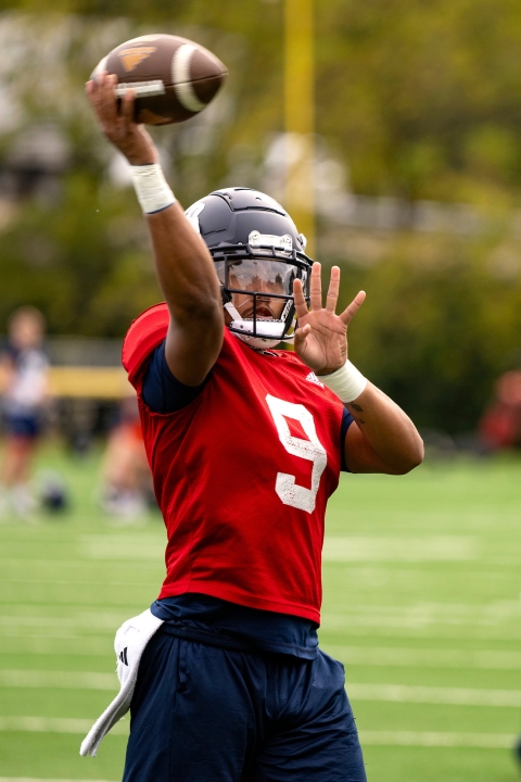 Michael Hardway &#039;25 wears a football uniform and helmet and is about to throw a football on the field.