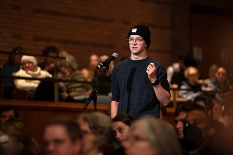 A male student wearing a knit hat asks a question to Jake Tapper from the crowd at a Bucknell Forum event.