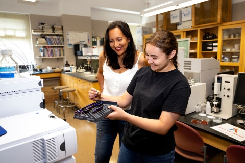 Jacquelyn Awigena-Cook &#039;05 looks on as Brianna Bolorin &#039;24 holds lab equipment in a lab.