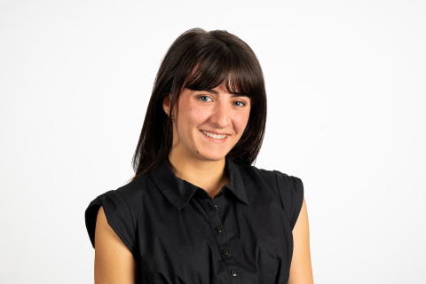 Alexis Killeen wears a black shirt and smiles against a white backdrop