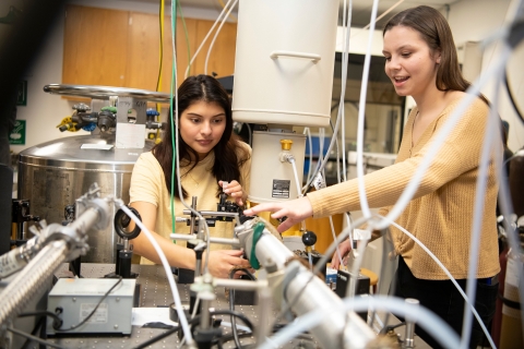 Anna Islas and Jewel Cook in a chemistry lab surrounded by tubing.