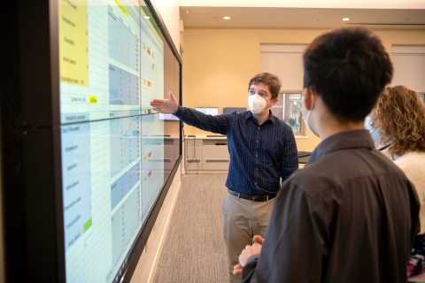 Student pointing at a display to other students. 