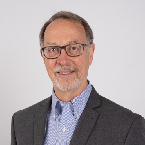 Portrait of a man with glasses, a blue oxford shirt, and grey sport coat.