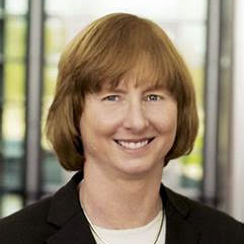A portrait of a woman in a white top with a black jacket