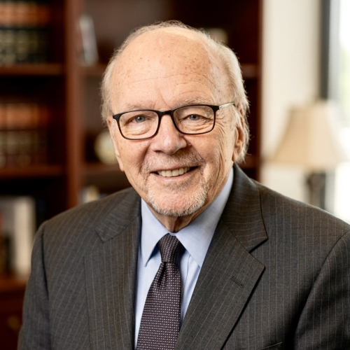 A portrait of a man in a gray suit with a blue shirt and navy tie.